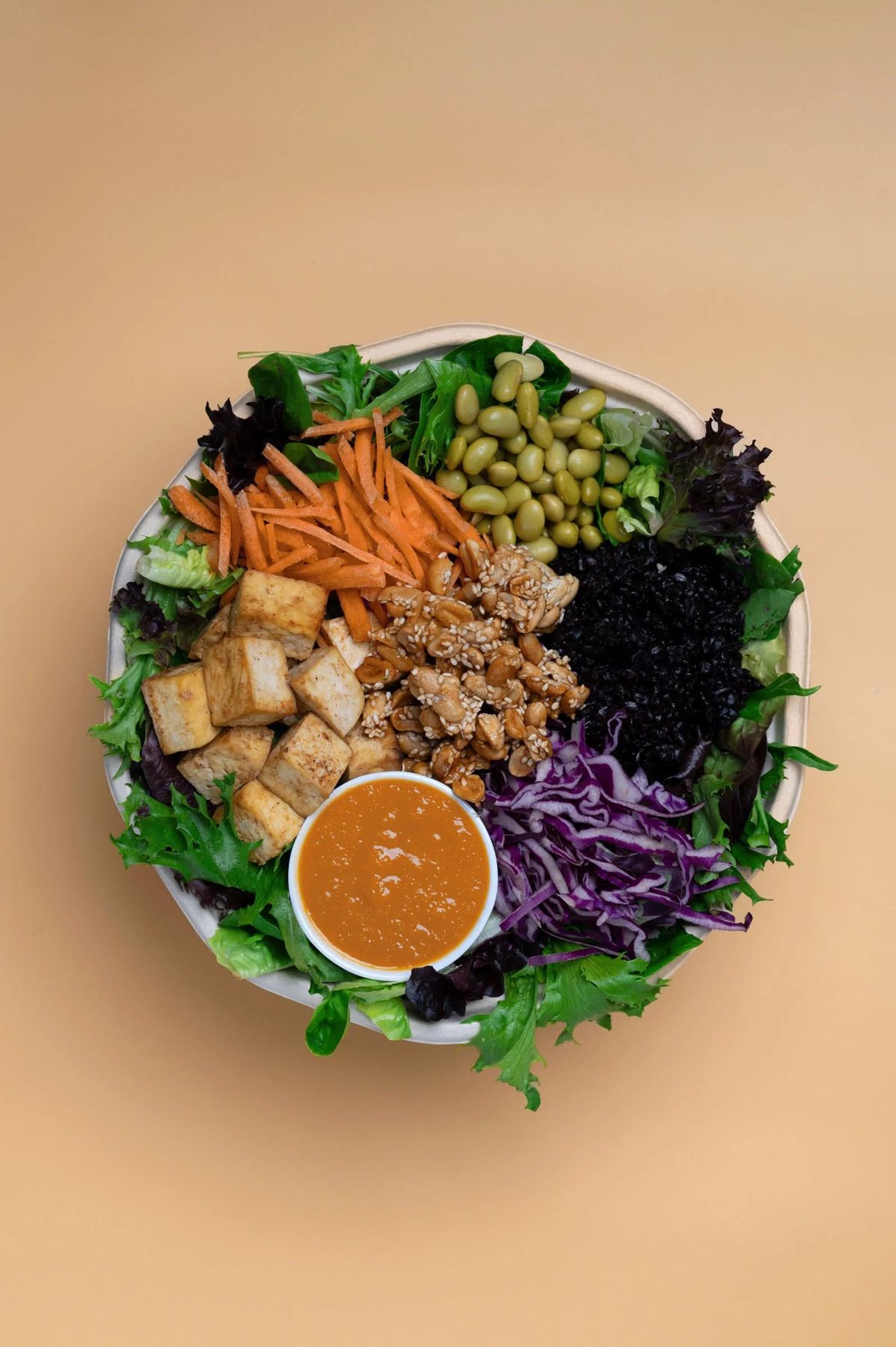 Top down Butterleaf bowl with tofu, edamame, black rice, red cabbage and satay dressing.