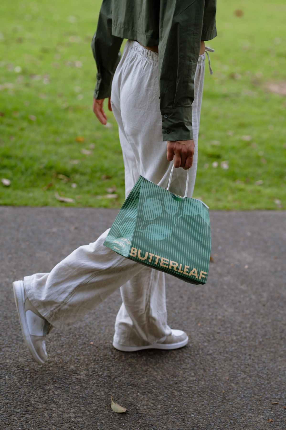 A customer carrying a Butterleaf takeaway bag through the park.
