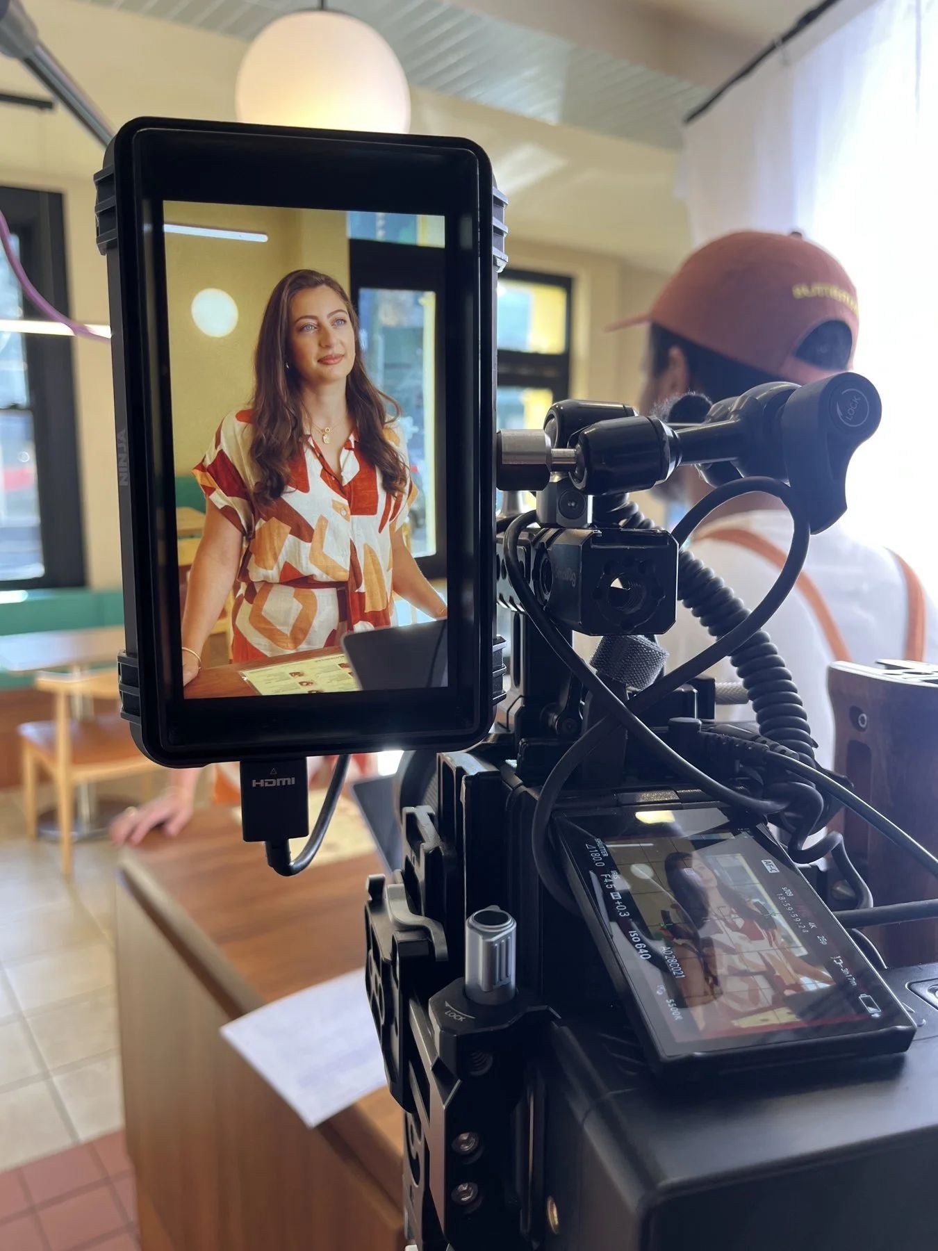 A monitor on set framing a customer talking to camera inside the finished store.