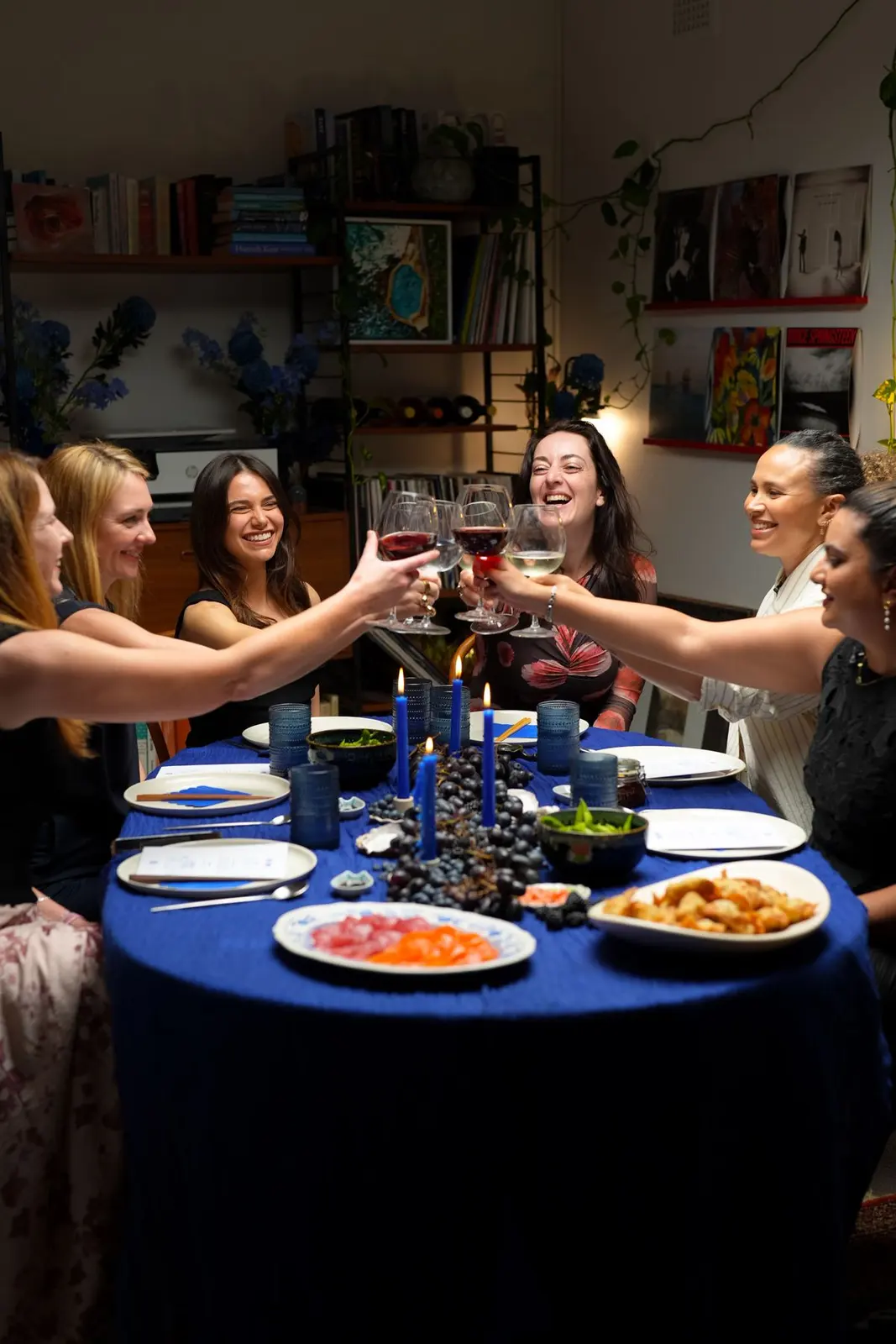 Guests reaching across the blue table to clink glasses.