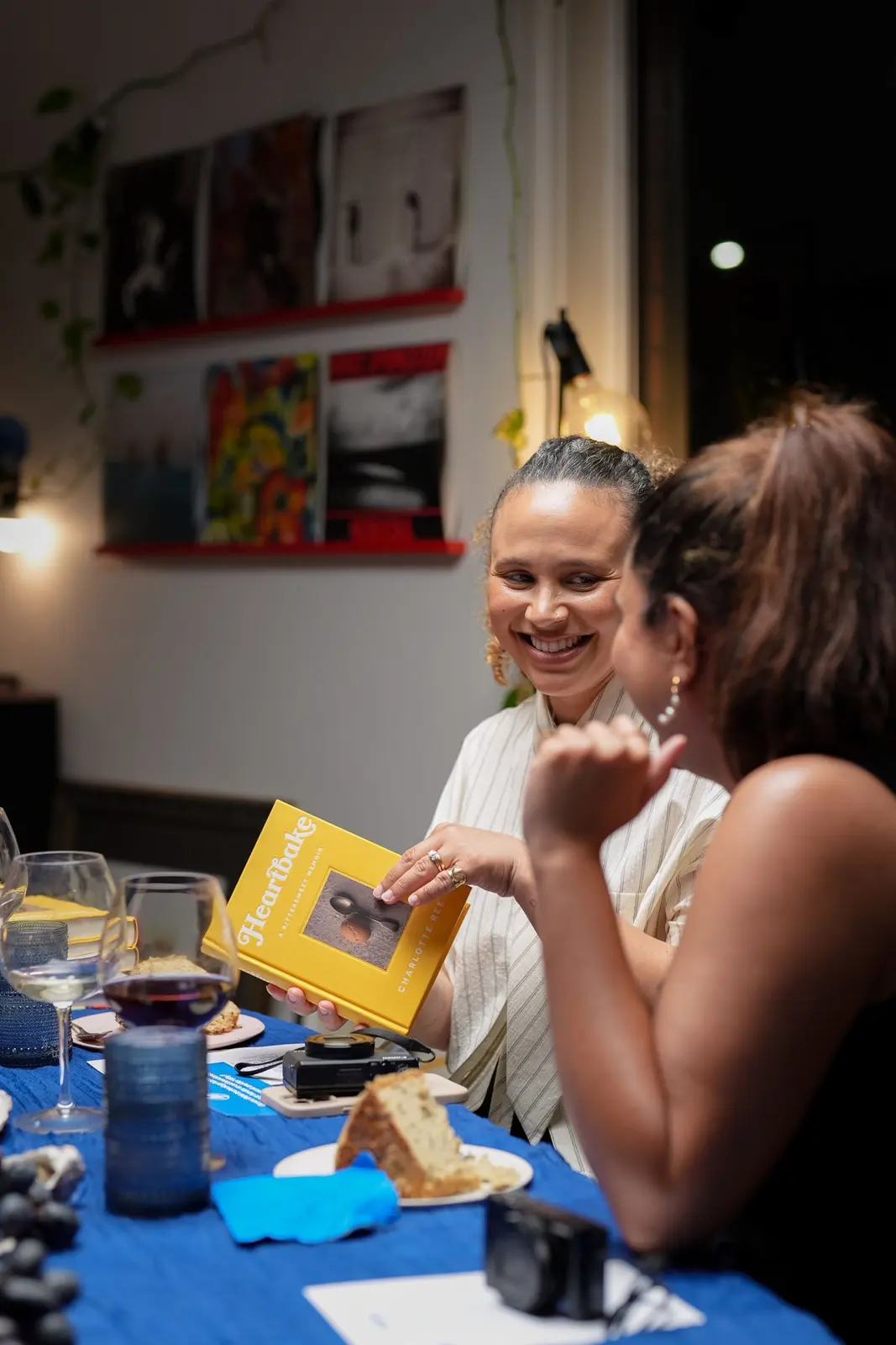 Two guests laughing as one holds up a copy of the book Heartbake by Charlotte Ree.